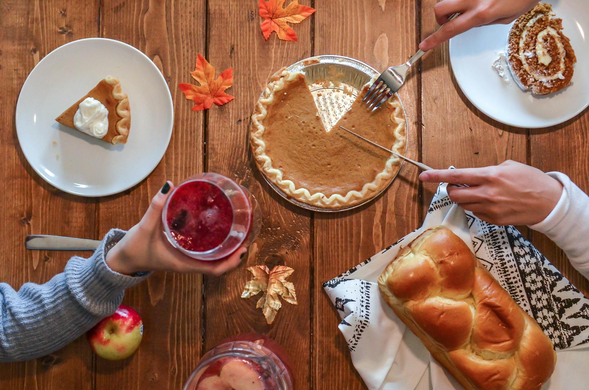 Thanksgiving feast with pumpkin pie, different kinds of desserts and beverages.