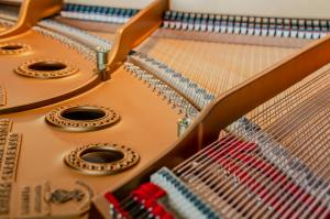 Close-up view of the interior mechanism of a grand piano, showcasing strings and hammers.